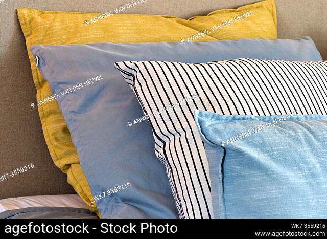 Closeup of Yellow and light blue pillows in a row on the bed, modern retro decoration for home, pastel light colors colorful bright background