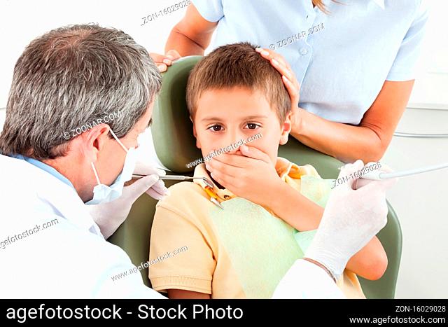 Junge beim Zahnarzt ist ängstlich und hält sich den Mund zu