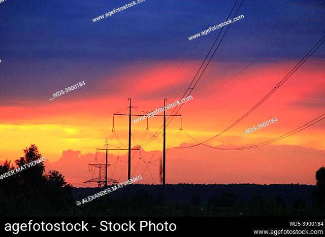 Sunset with crimson clouds and high-voltage line. Red decline. Evening panorama with fiery clouds