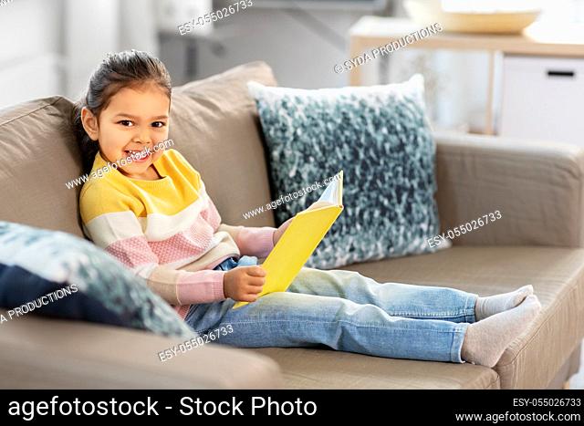 happy smiling little girl reading book at home