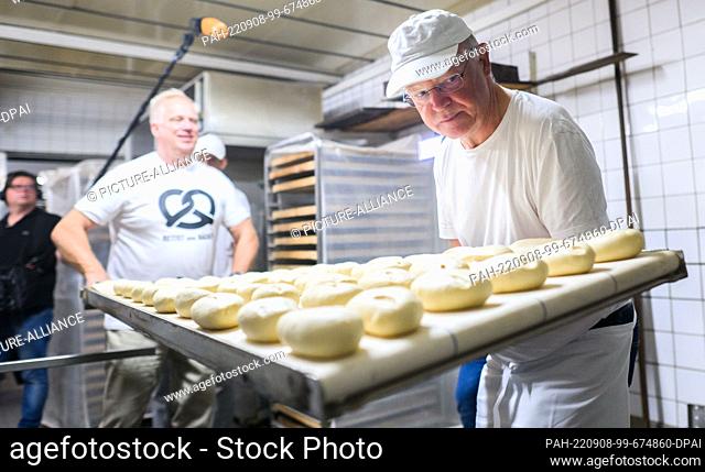 08 September 2022, Lower Saxony, Hanover: Stephan Weil (r, SPD), Minister President of Lower Saxony, puts rolls into an oven early this morning in the bakery of...