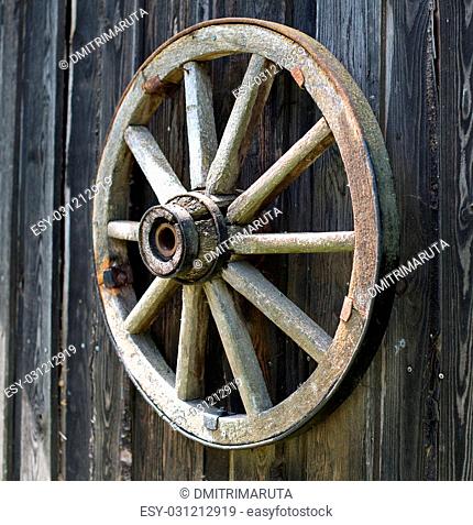 Old wooden carriage wheel hanging on the barn
