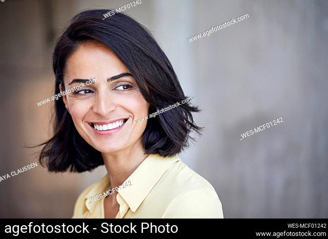 Close-up of happy businesswoman contemplating against wall in office