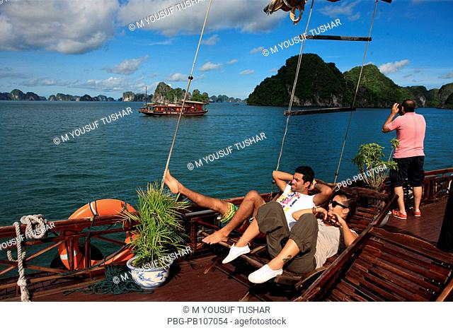 Tourists travelling on boat at Halong Bay It is located in Quáng Ninh province, Vietnam The bay features thousands of limestone karsts and isles in various...
