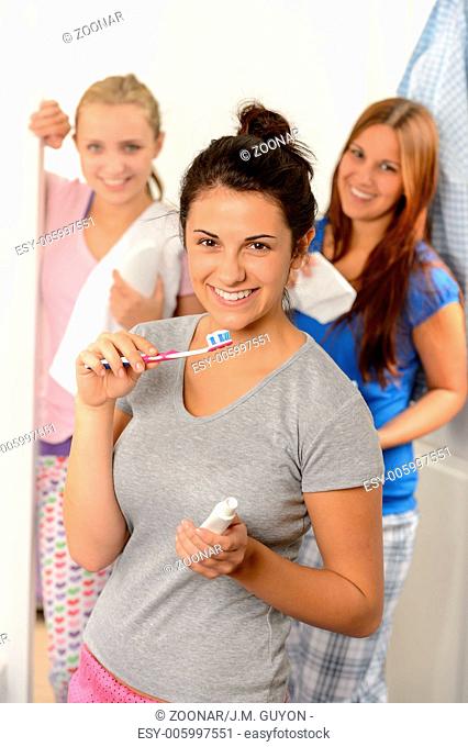 Teenage girl washing her teeth with friends