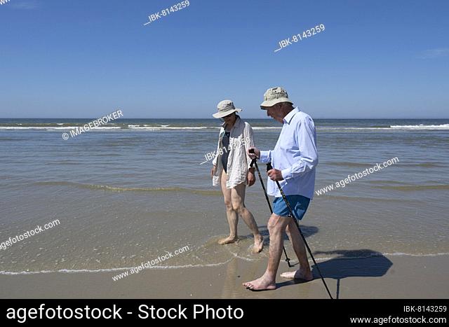 Elderly man accompanied by woman walking on the beach, Juist Island, North Sea, East Frisia, Lower Saxony, Germany, Europe