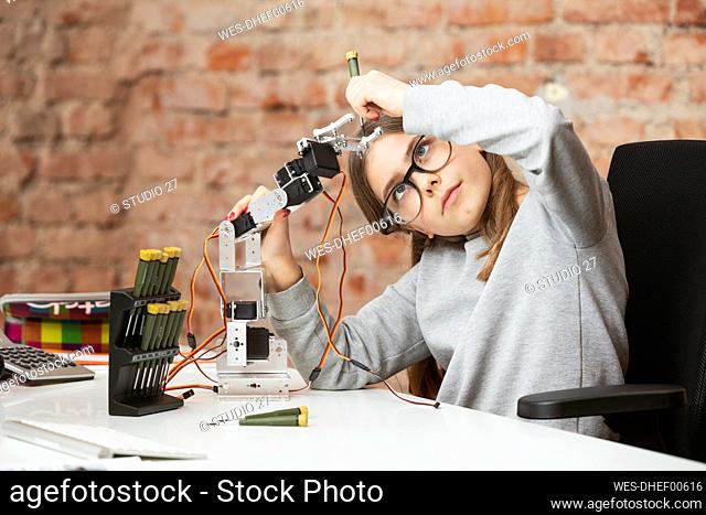 Girl doing scientific experiment on robotic arm at table