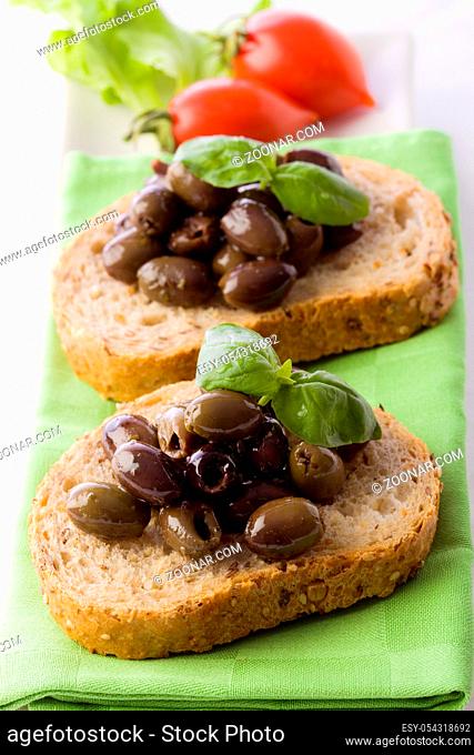 photo of delicious sliced bread with olives and basil
