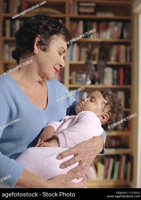 Middle-aged woman cradling her baby granddaughter