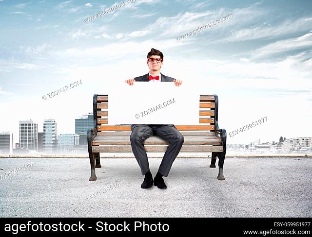 Young businessman holds a large white banner. sits on the bench