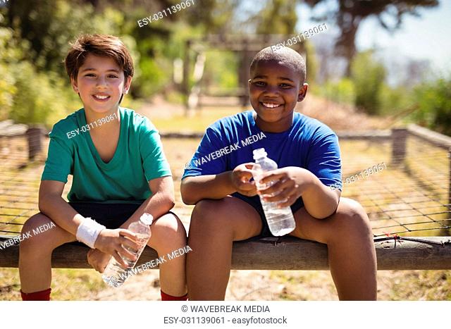 Portrait of smiling friends relaxing after workout during obstacle course