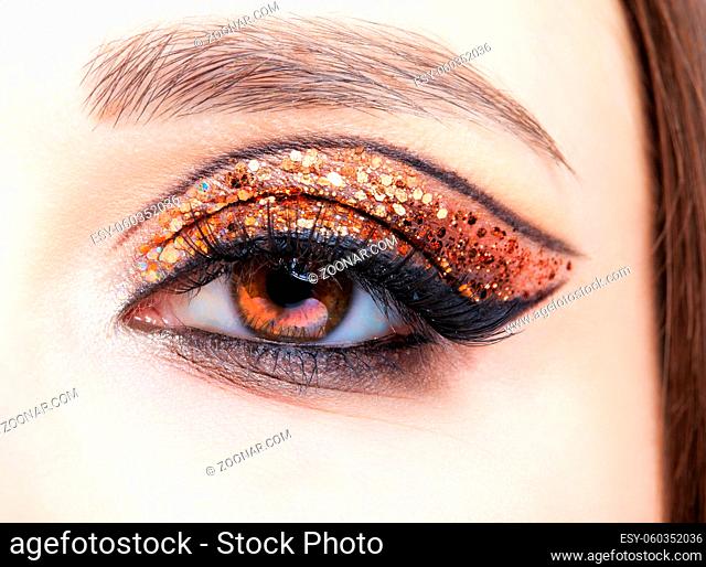 Close-up shot of female face with vogue golden shining eyes makeup