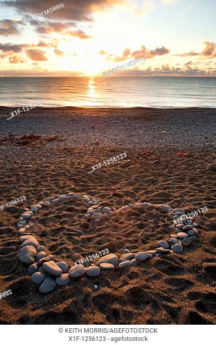 A heart shape made from pebbles at sunset on Aberystwyth beach wales UK