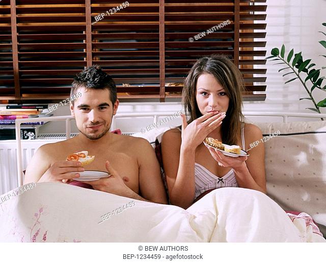 Couple eating in bed