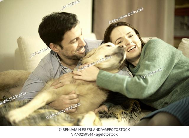 couple with dog laying on couch at home, in Munich, Germany