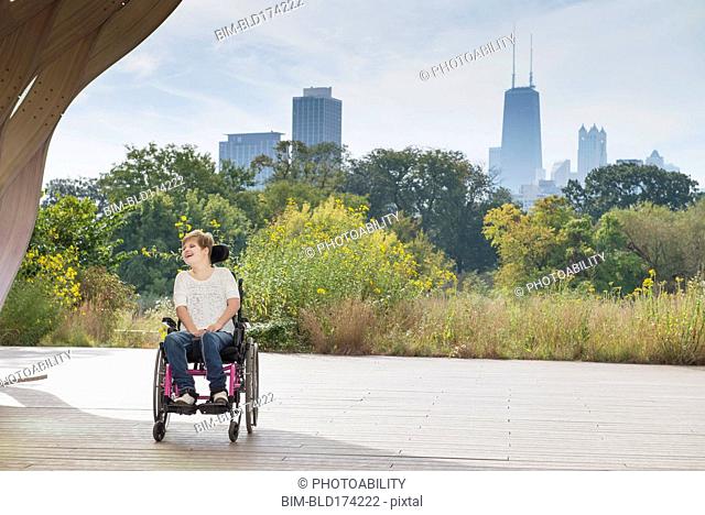 Paraplegic woman sitting in wheelchair under city skyline
