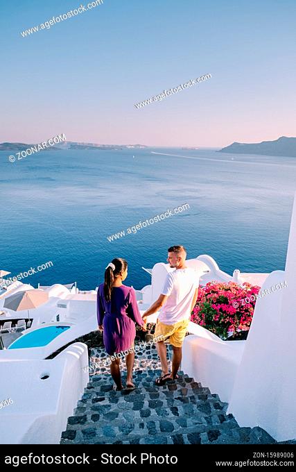 Santorini Greece, young couple on luxury vacation at the Island of Santorini watching sunrise by the blue dome church and whitewashed village of Oia Santorini...