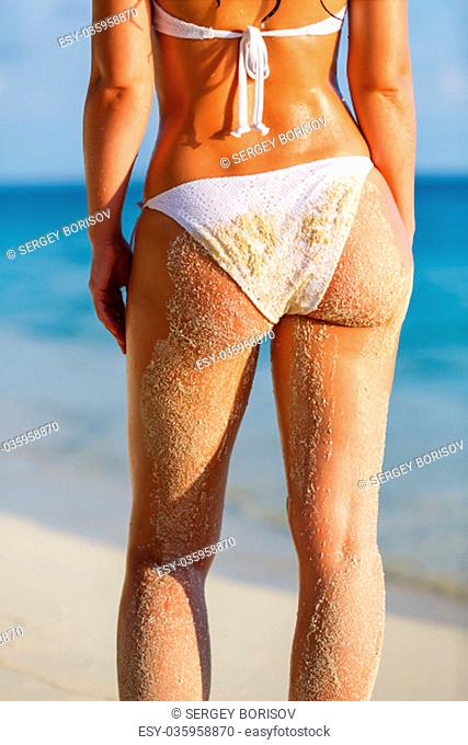 Back of young woman in bikini standing on the beach