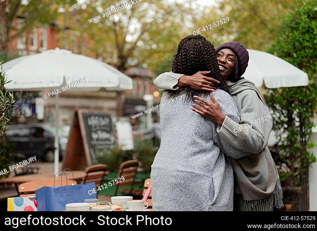 Happy mother and daughter hugging at cafe patio