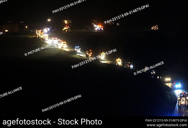 15 December 2023, North Rhine-Westphalia, Kürten: Tractors drive along a road illuminated with fairy lights during a tractor light drive