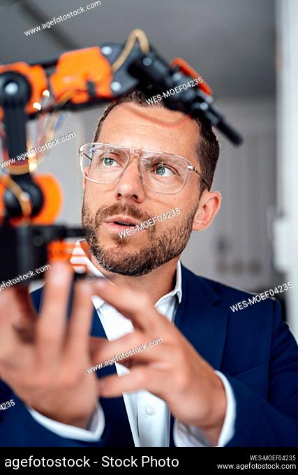 Businessman wearing eyeglasses examining robotic model