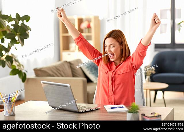 happy woman with laptop working at home office