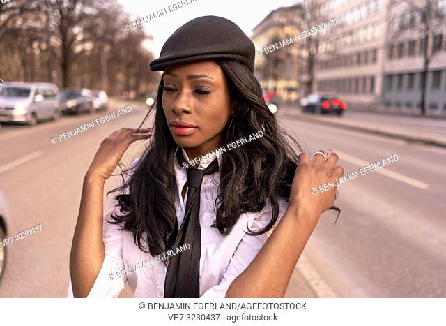 retro style business woman in evening sunlight at street, African Angolan descent, in city Munich, Germany