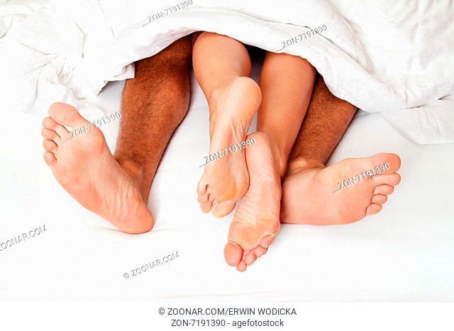 Dier Füße eines Paares im Bett. Liebe, Erotik und Partner