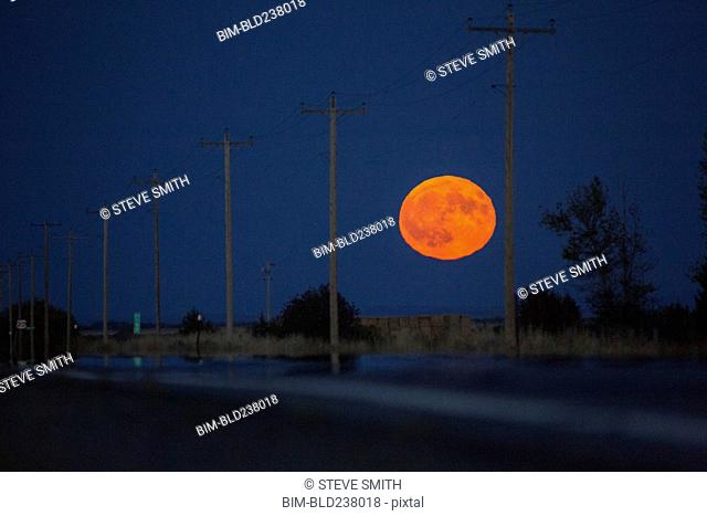 Orange full moon over utility poles