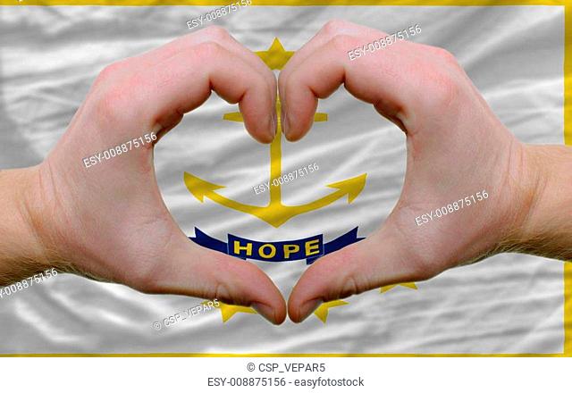 Gesture made by hands showing symbol of heart and love over us state flag of rhode island