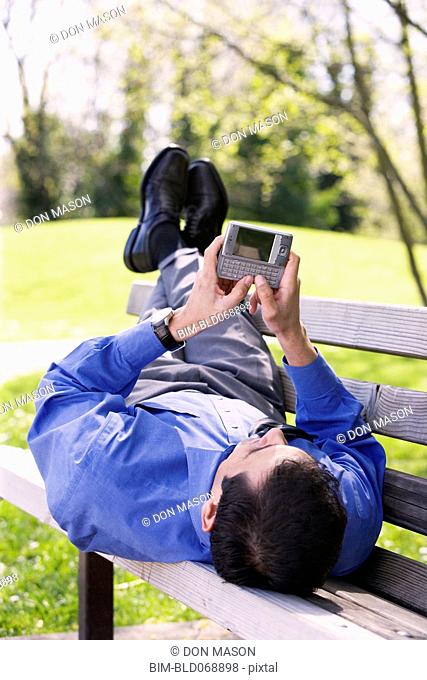 Hispanic businessman using PDA outdoors