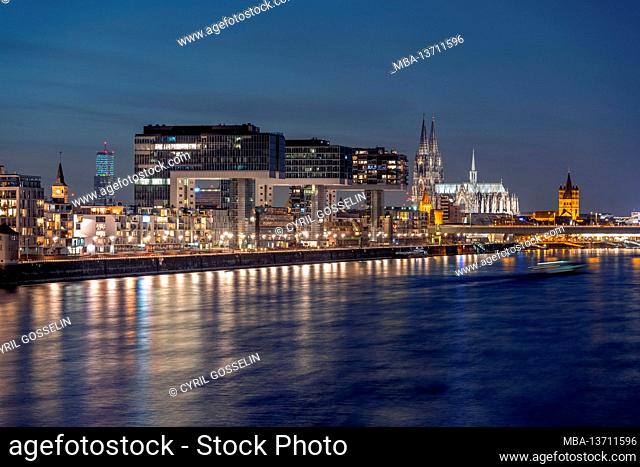 Crane houses on the banks of the Rhine at dusk, with Cologne Cathedral in the background