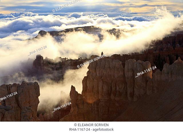Fog and clouds of a partial temperature inversion surround the red rocks of Bryce Canyon, Bryce Canyon National Park, Utah, United States of America