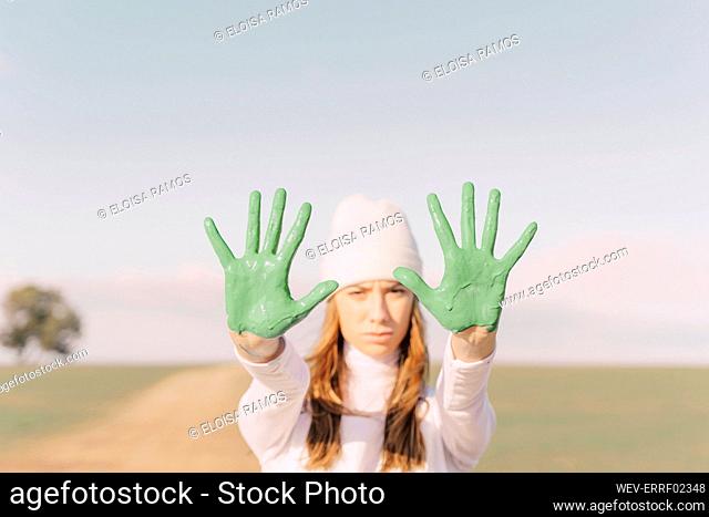 Young woman showing green painted palms