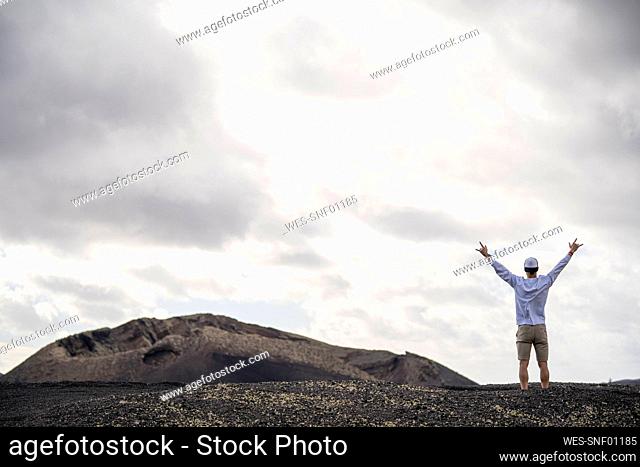 Male tourist with arms outstretched standing at volcanic landscape