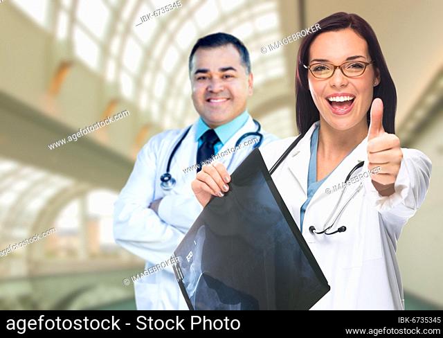 Doctors or nurses with thumbs up holding x-ray standing inside hospital