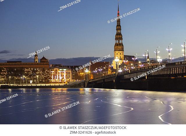 Winter dawn in Riga, Latvia, seen across partially frozen Daugava river. St Peter's church dominates the skyline