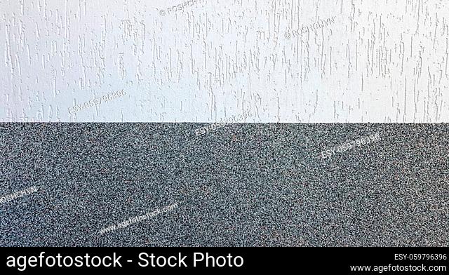 Gray marble chips and decorative light stucco on the wall divided by a horizontal line. Building facade background. Stucco texture on the street