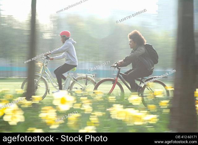 Teen friends riding bicycles in sunny spring park