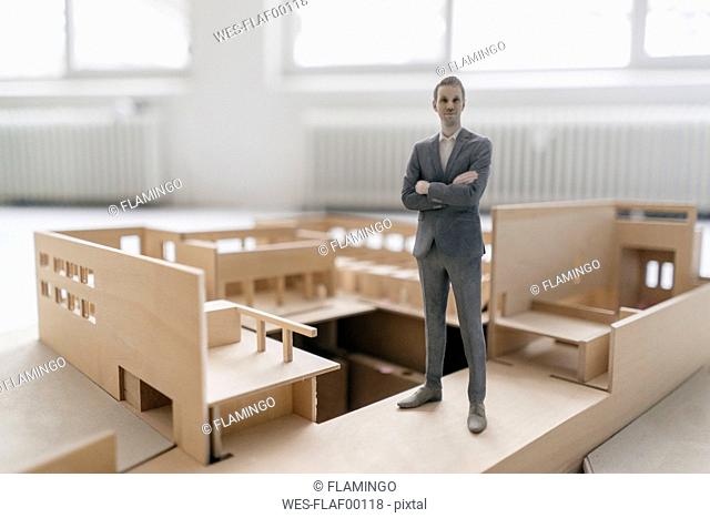 Miniature businessman figurine standing in architectural model