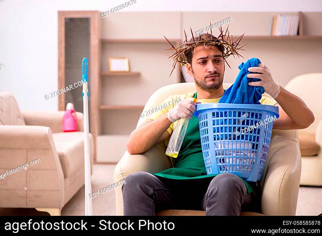 Young male contractor wearing prickly wreath on head doing housework