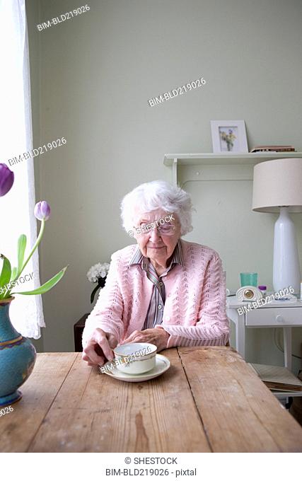Older woman drinking tea at table