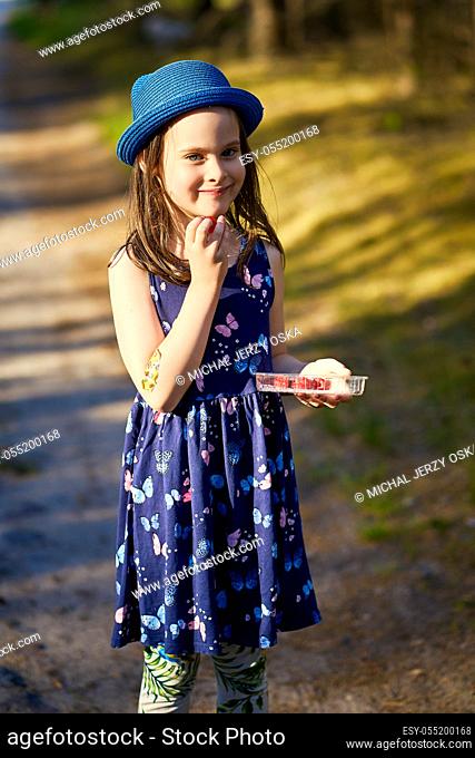 adorable little girl in a blue hat posing in the spring pine forest
