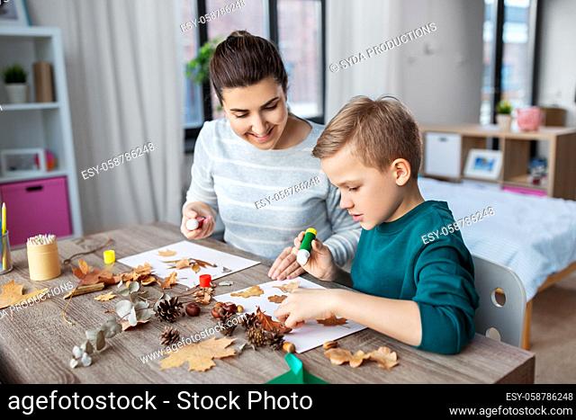 mother and son making pictures of autumn leaves