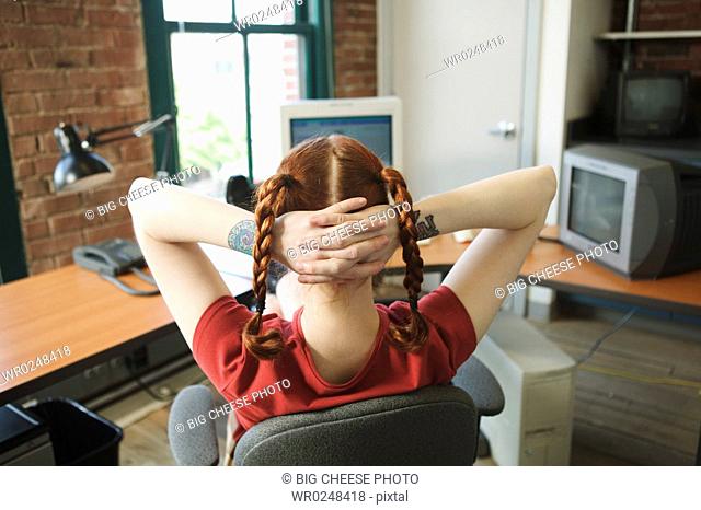 Red-haired woman leaning back at her office desk