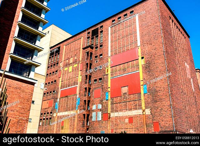 Colorful and artful facade of old abandoned industrial ruin. Windows and doors sealed with metal plates and corrugated metal sheets. Berlin, Germany