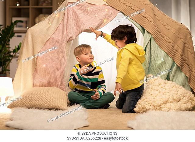 happy boys with torch light in kids tent at home