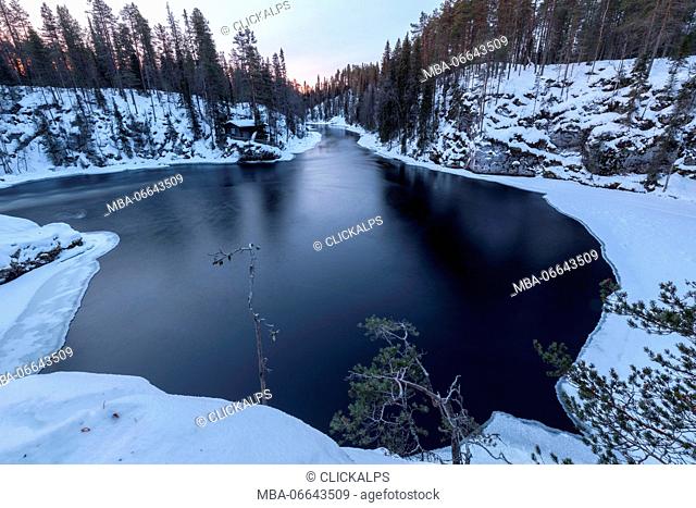 The snowy woods framed by frozen water and blue lights of dusk Juuma Myllykoski Lapland region Finland Europe