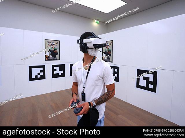 06 July 2021, Baden-Wuerttemberg, Stuttgart: A visitor to the art museum stands with virtual reality glasses on in a room in which only QR codes hang on the...