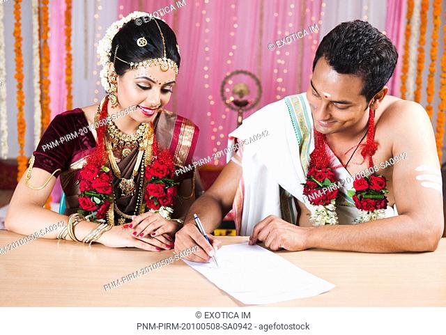 Newlywed couple signing a marriage certificate